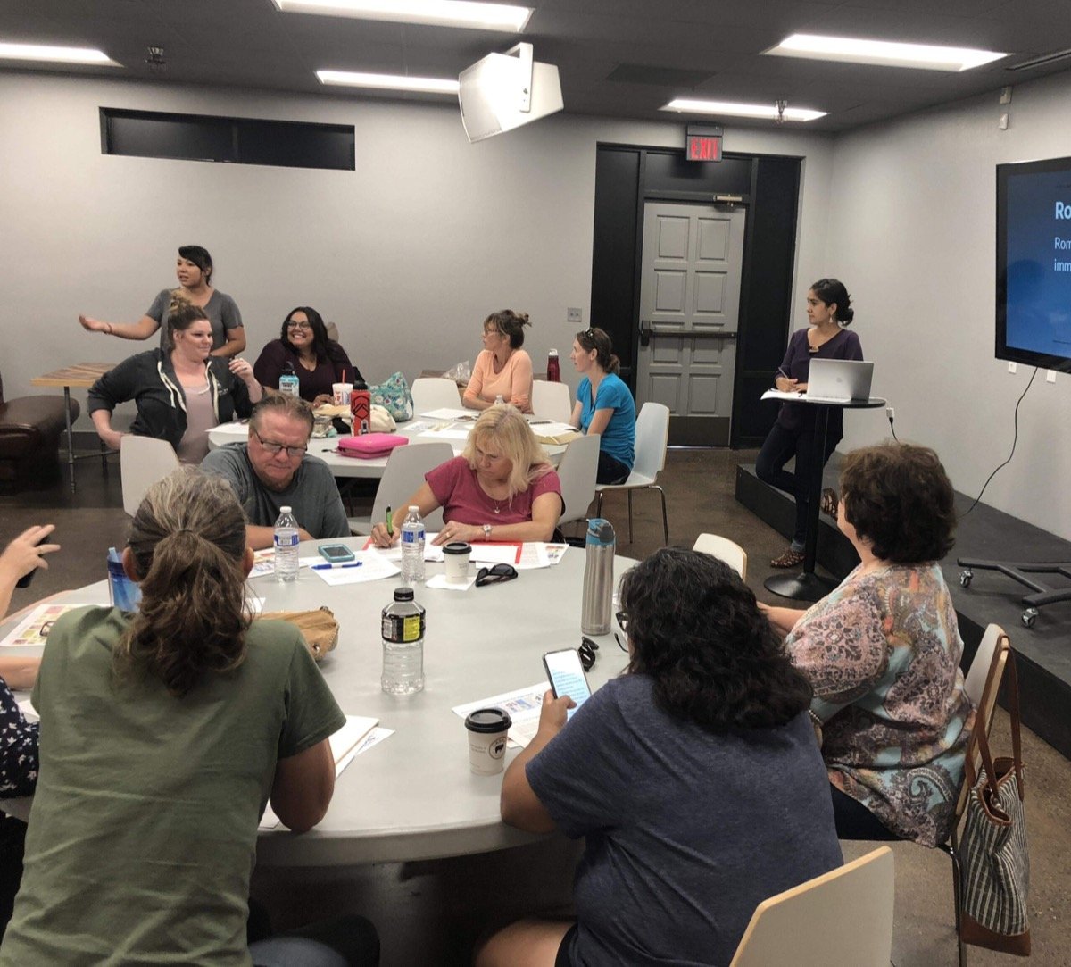 Residents working in small groups around tables at a neighborhood planning meeting