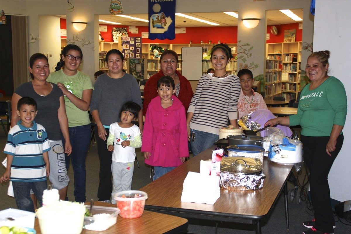 Parents and children gathered around tables in a school library at a parent engagement event